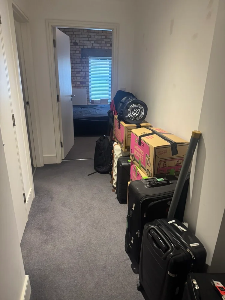 Suitcases and packed moving boxes lined up in a flat hallway