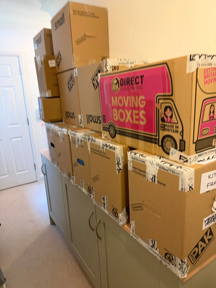 Labelled moving boxes packed and stacked in a bedroom before moving day