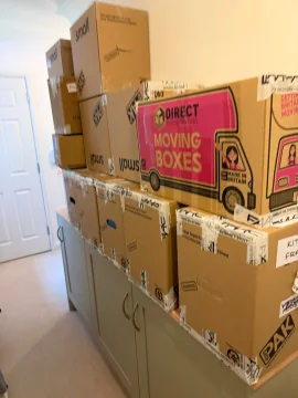 Labelled moving boxes packed and stacked in a bedroom before moving day