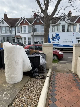 Wrapped mattress and household items being carried out to the van