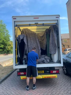 SJC mover securing blanket-wrapped furniture in the van