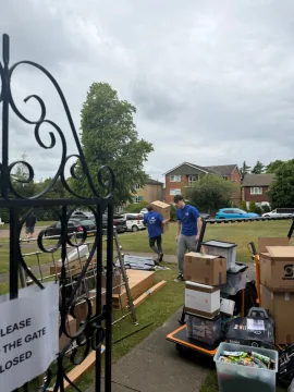 SJC Movers team in uniform carrying boxes across a garden on moving day