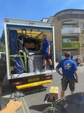 SJC Movers team loading a wrapped mattress into the van outside a block of flats