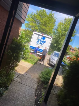 SJC Movers van arriving on the driveway at a customer's home