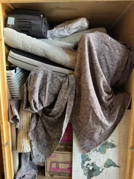 Storage container packed with rugs, blankets and household items