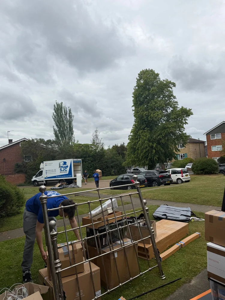 SJC Movers team loading a bed frame and boxes with the van waiting nearby
