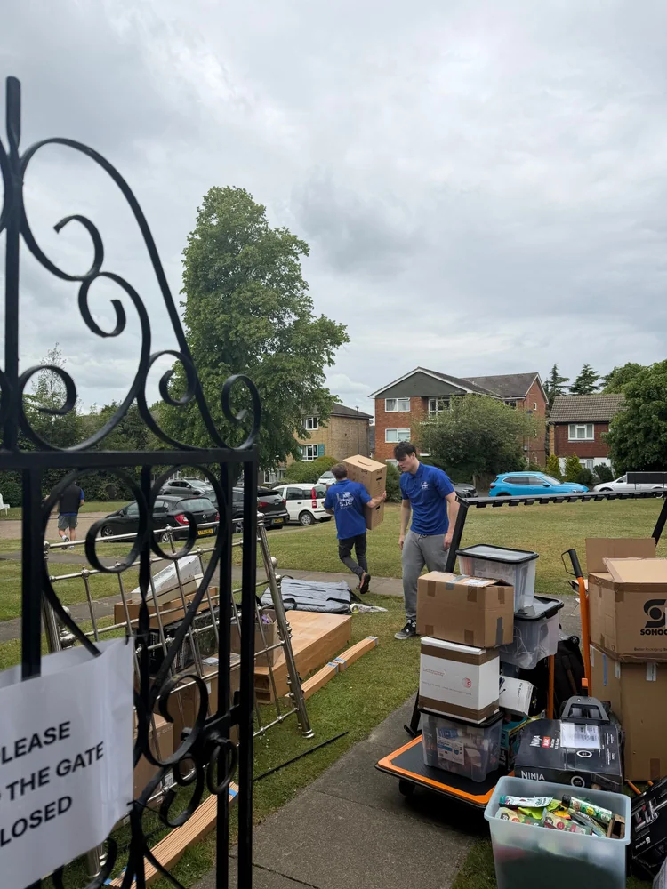 SJC Movers team in uniform carrying boxes across a garden on moving day