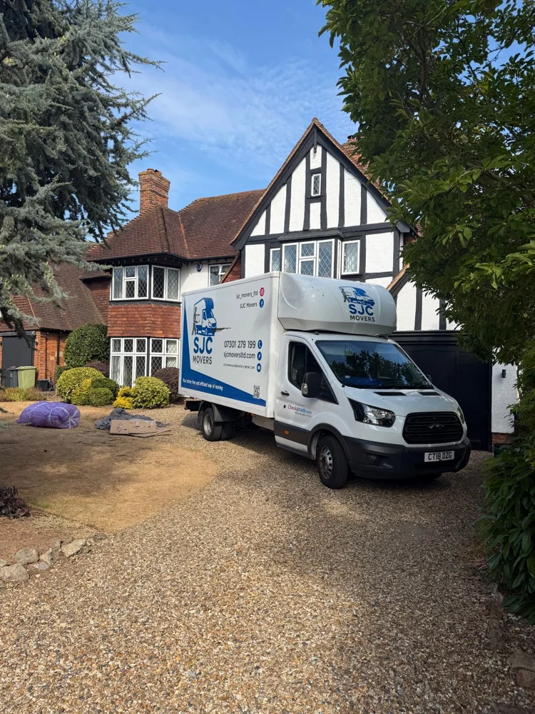 SJC Movers van parked on the driveway of a detached house on moving day